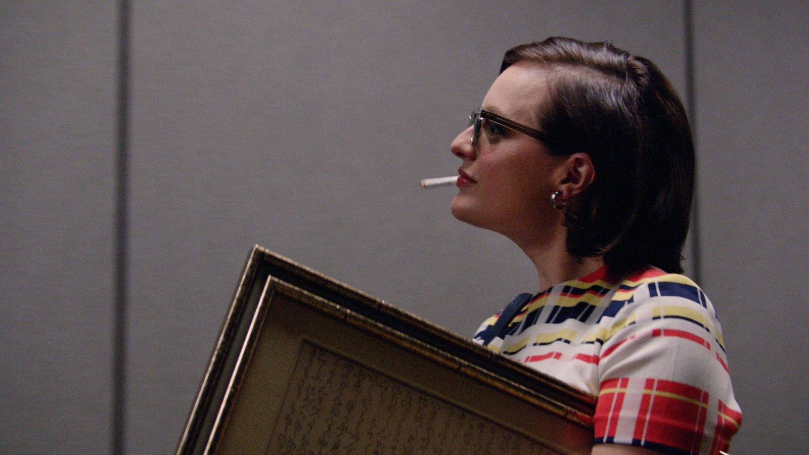 Peggy (Elizabeth Moss) sorri enquanto cruza o corredor em Mad Men