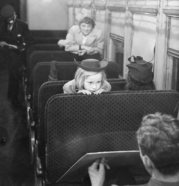 Foto de uma criança espiando um homem a alguns assentos de distância no trem